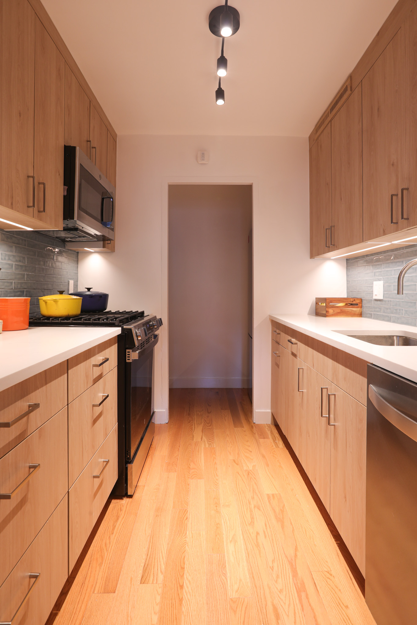 Galley kitchen — rift oak cabinetry and slate-blue subway tile